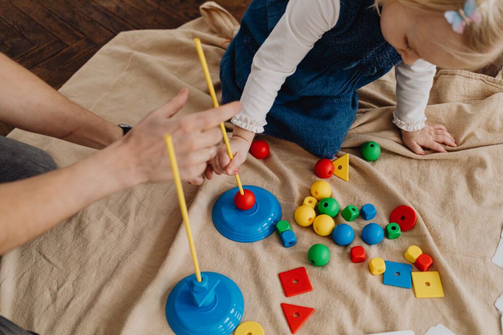 pexels photo 7296459 A child playing with educational toys, learning shapes and colors with a supervising adult.